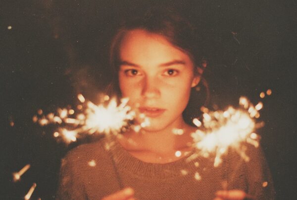 A young girl holds sparklers in the dark, her expression calm and focused, illuminating the quiet emotional intensity often behind the question, does my child need therapy.