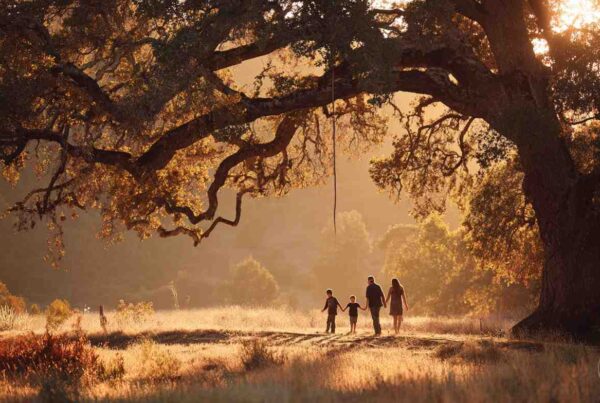 A family walks beneath a large oak tree at sunset, symbolizing unity and the question: does my family need therapy?