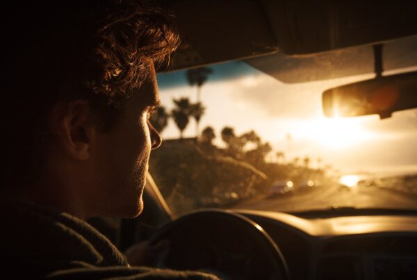 Man driving at sunset, lost in thought as if he might cry for no reason.