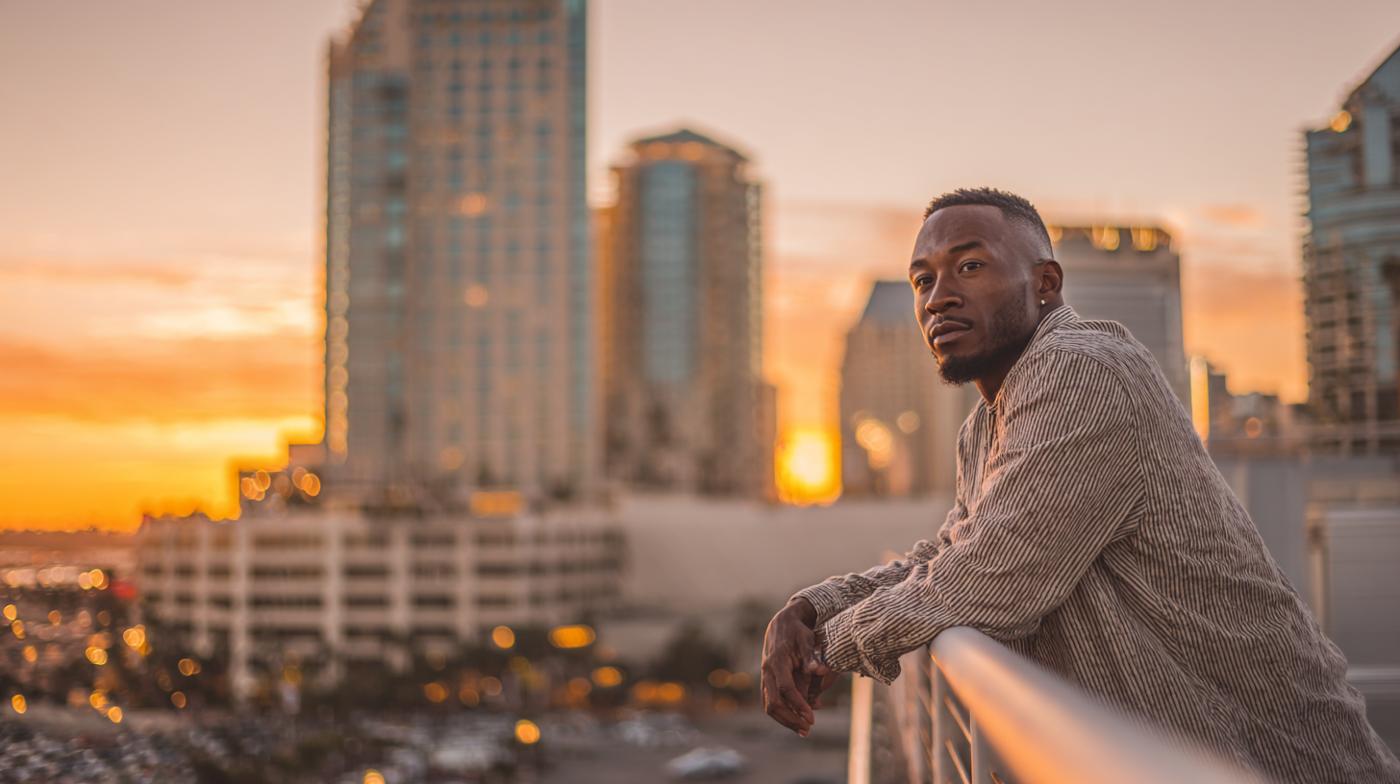 A man leaning on a railing at sunset in a city skyline, appearing deep in thought as the stages of anxiety shift beneath the surface.