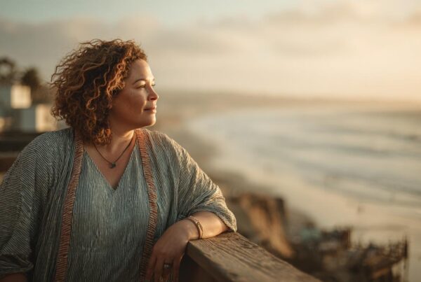 A woman stands alone overlooking the ocean at sunset, reflecting a moment of clarity often reached after recognizing emotional manipulation.